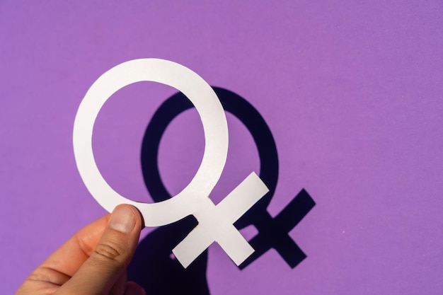 A woman holding the female symbol on a purple background, march for women's rights and equality, with spring shadow