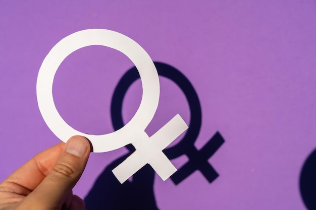 A woman holding the female symbol on a purple background, march for women's rights and equality, with spring shadow