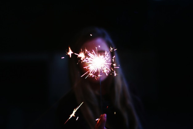 Foto donna con i fuochi d'artificio di notte