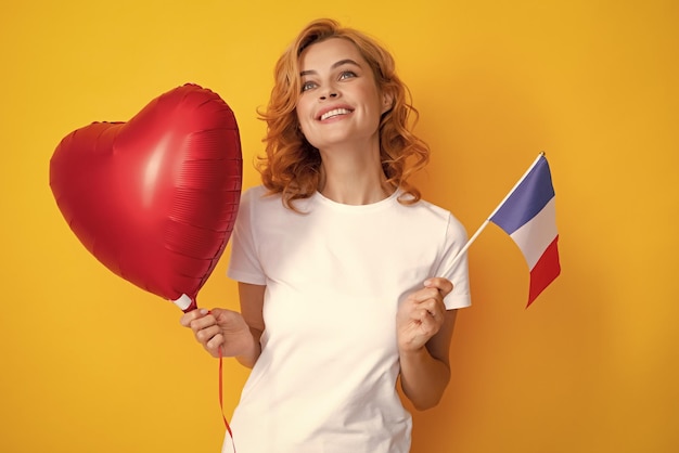 Woman holding flag of France and red heart balloon Student holding france flag Isolated on yellow background