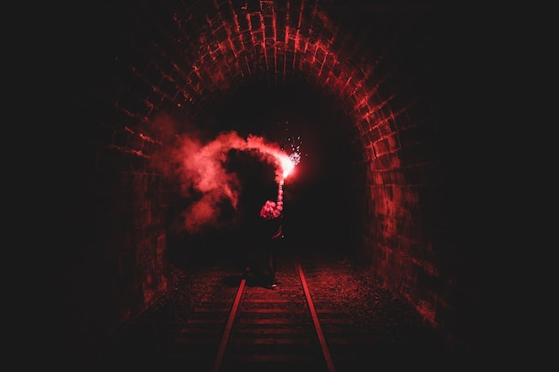 Photo woman holding flame torch in dark tunnel