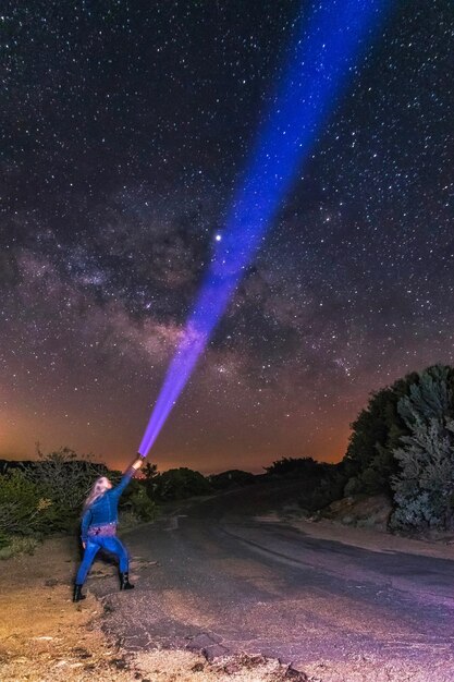 Foto donna con la torcia verso il campo stellare nel campo contro il cielo di notte