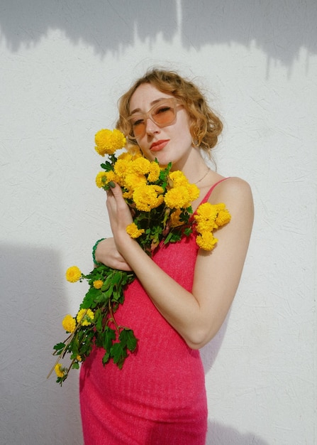 Woman holding flower bouquet against wall