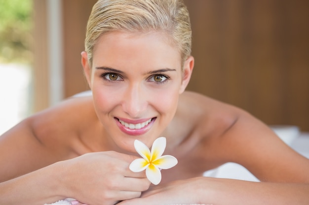 Foto fiore della holding della donna sulla tabella di massaggio al centro della stazione termale