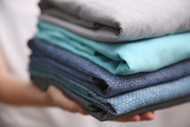 Woman holding folded clothes in hands closeup