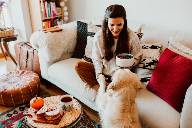 家で犬と遊んでいる女性が食べ物を握っている