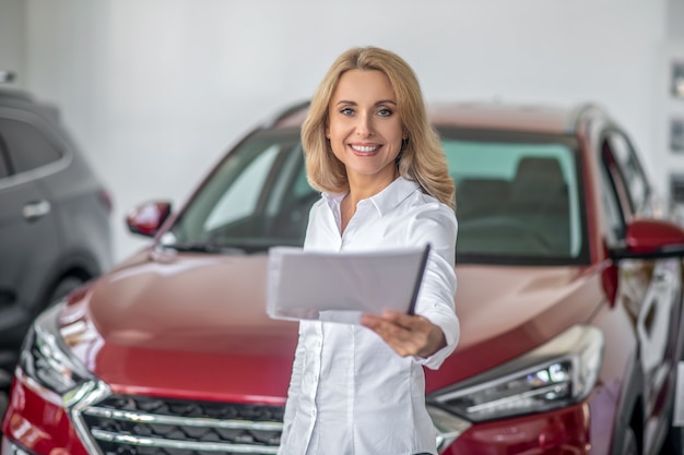 Woman holding forward paper in car dealership