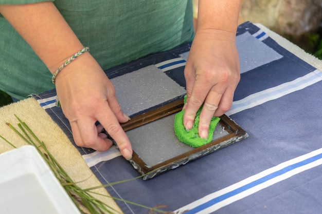 Donna che mantiene il telaio per la produzione di fogli di carta dalla pasta di carta straccia. messa a fuoco selettiva. arte decorativa e applicata. concetto di riciclaggio, ecologia.