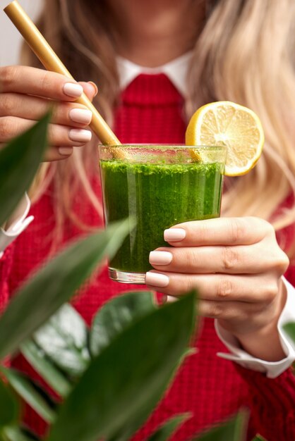 Photo woman holding fresh spinach green smoothie with bamboo straw