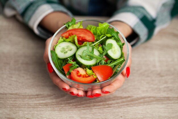 Woman holding fresh vegetable salad in a transparent plate