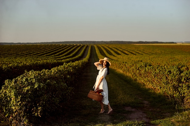 Photo woman holding fruit basket in front of currant field.