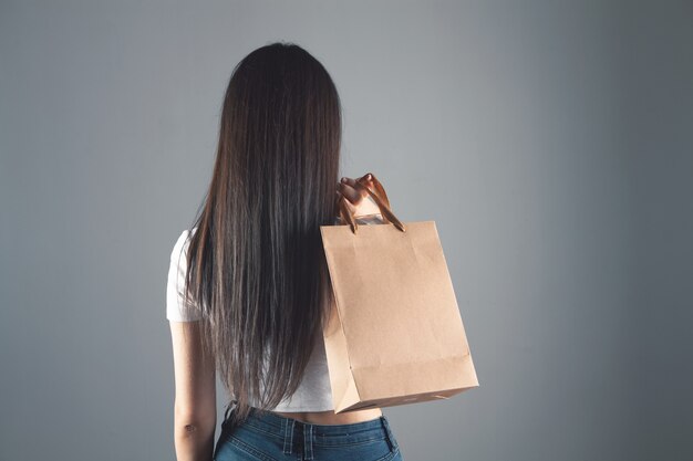 Woman holding gift bags on gray background