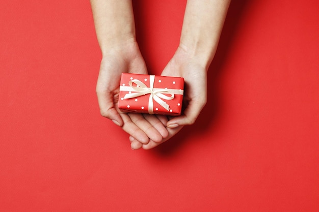 Woman holding gift box on color background, top view