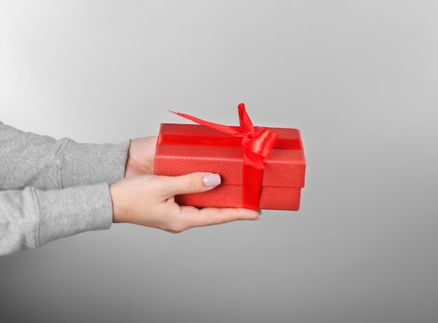 Woman holding gift box on color background