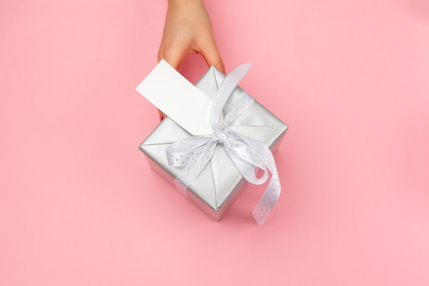 Woman holding gift box on color background