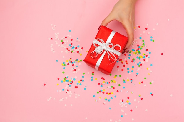 Woman holding gift box on color background