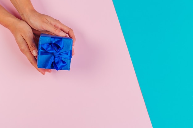 Woman holding gift box on color background