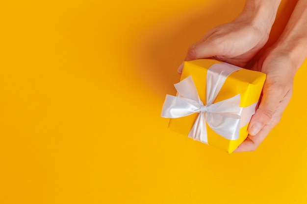 Woman holding gift box on color background