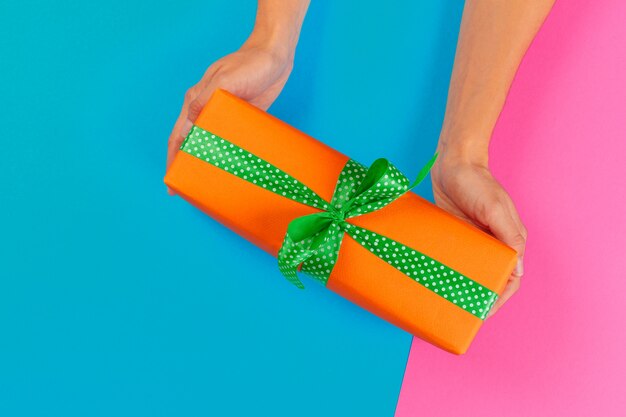 Woman holding gift box on color background