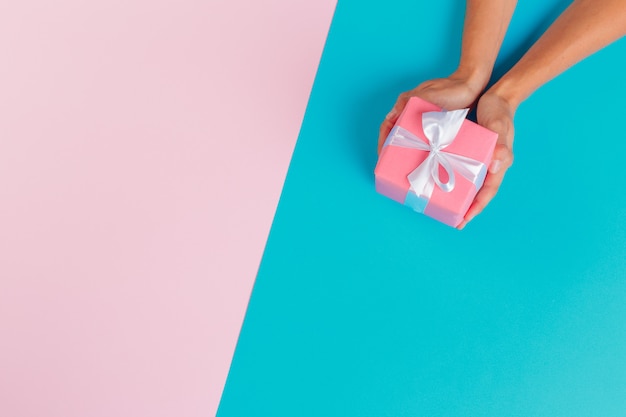 Женщина держит подарочную коробку на цветном фоне