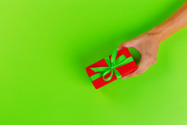 Woman holding gift box on color 