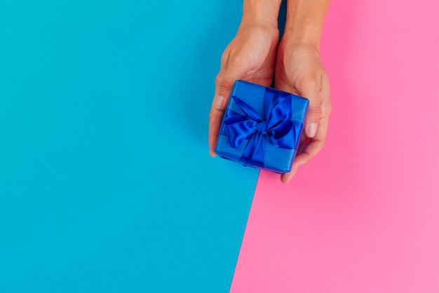 Woman holding gift box on color 