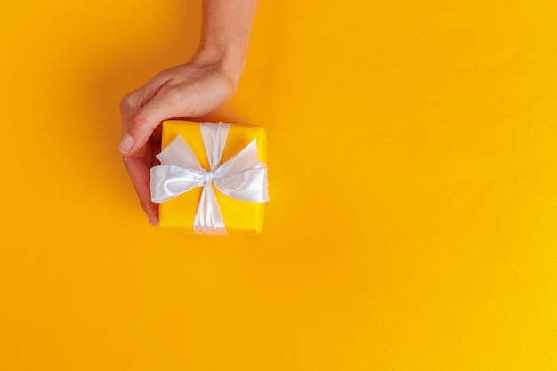 Woman holding gift box on color