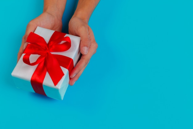 Woman holding gift box on color 