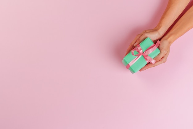 Woman holding gift box on color 