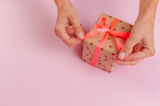 Woman holding gift box on color 