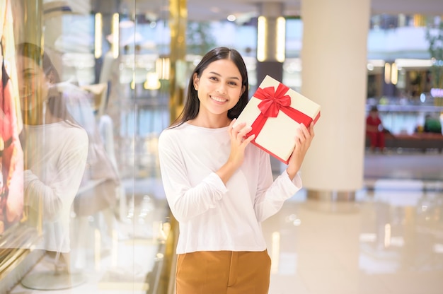 A woman holding a gift box in shopping mall