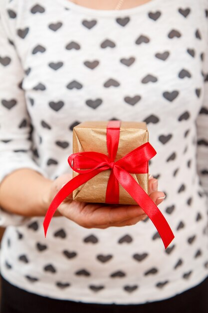 Woman holding a gift box tied with red ribbon in her hand