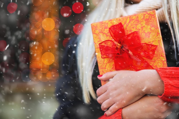 Foto contenitore di regalo della tenuta della donna alla fiera di inverno durante la nevicata. spazio per il testo