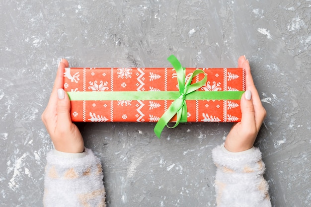 Woman holding gift box with colored ribbon