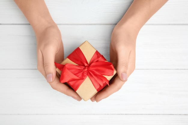 woman holding gift box on wooden background