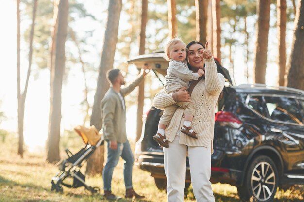 Photo woman holding girl happy family of father mother and little daughter is in the forest