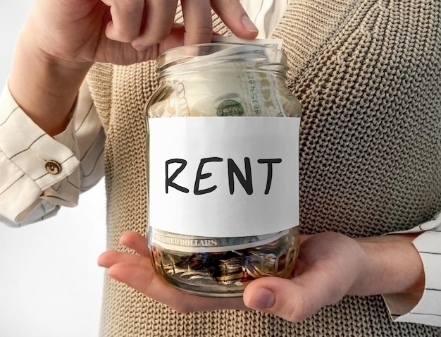 単語 Rent でお金の入ったガラスの瓶を保持している女性