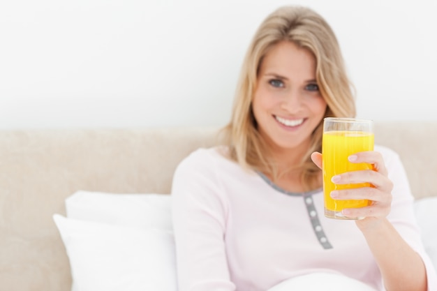 Woman holding a glass of orange juice while smiling and looking ahead