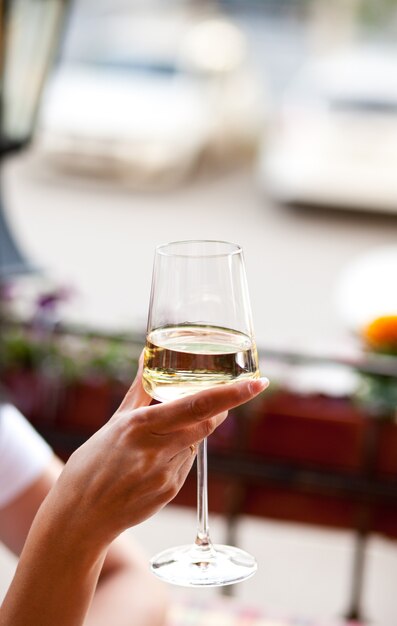 Woman holding a glass with white wine in a cafe.