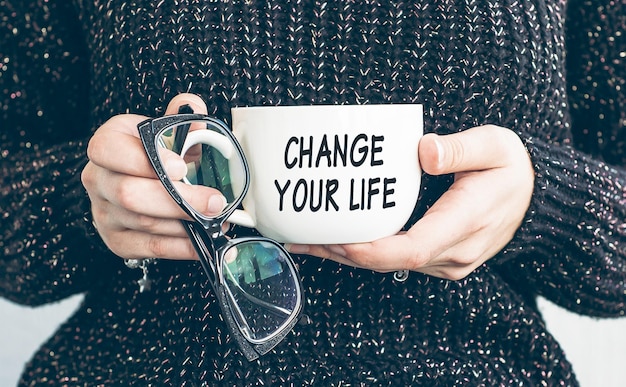 Woman holding glasses and mug of coffee with Change your life text