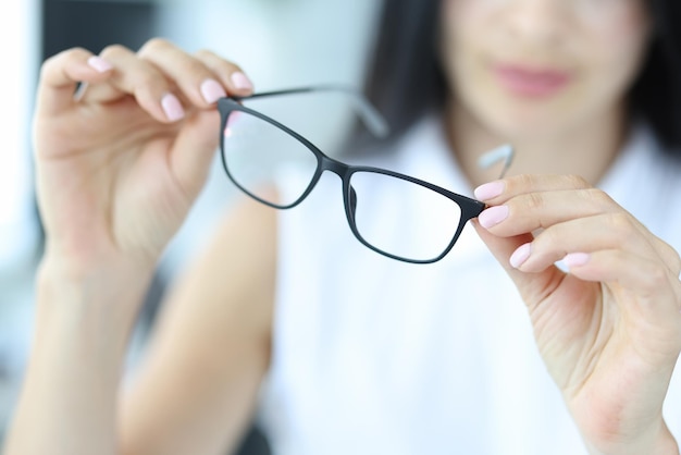 ビジョンのクローズアップのための眼鏡を保持している女性