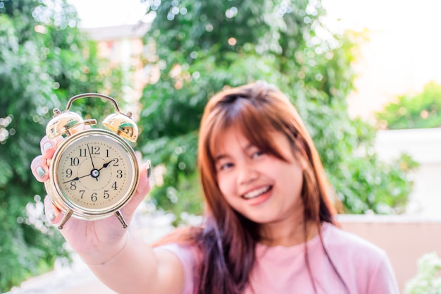 Woman holding a golden alarm clock.