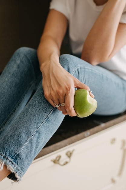 Woman holding a green apple with bite