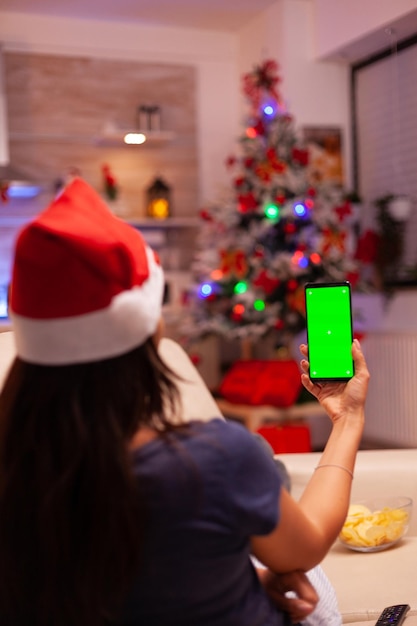 Woman holding green screen mock up chroma key phone with isolated display sitting