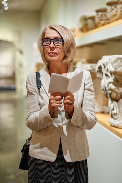 Woman Holding a Guide Inside a Museum