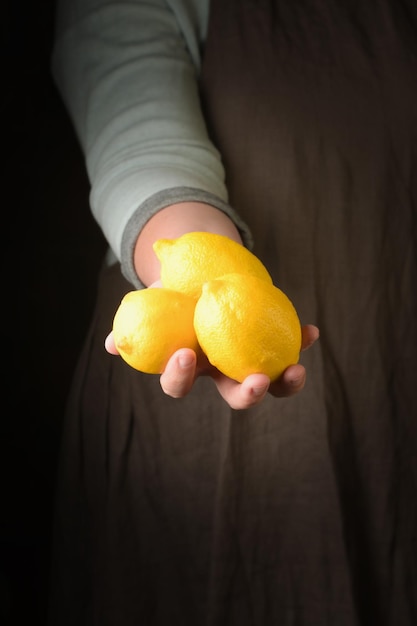 Woman holding in hand freshly harvested lemon closeup