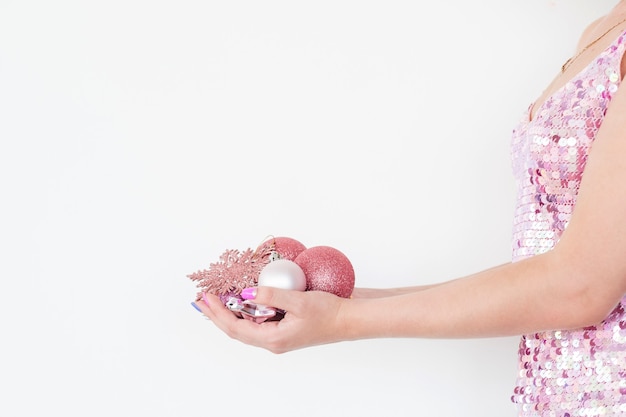 woman holding handful of rose gold glittery baubles on white