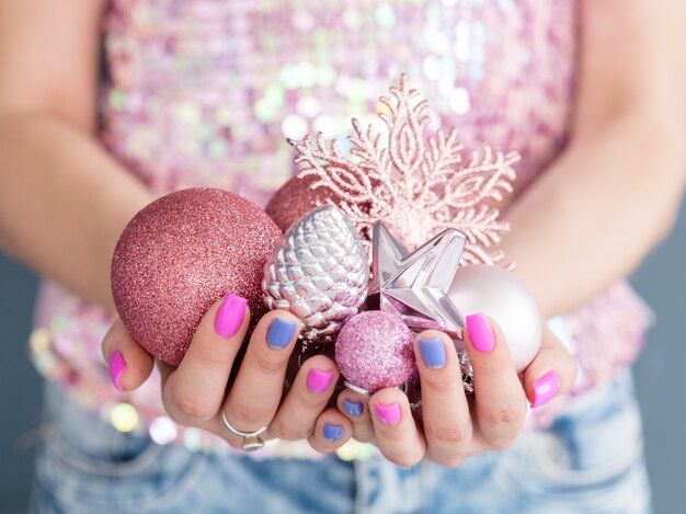 Photo woman holding handful of traditional seasonal toys. rose gold glittery baubles snowflake pine and star.
