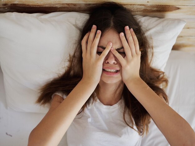 woman holding hands on face upset crying lying in bed High quality photo