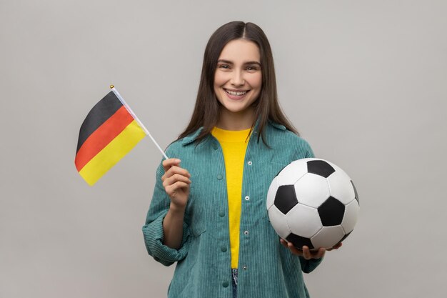 Woman holding in hands flag of Germany and football ball supporting favourite team on championship